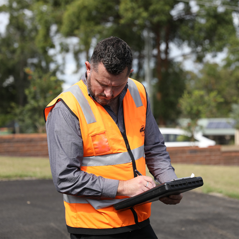 Adam Pinkerton with clipboard assessing an asphalt project